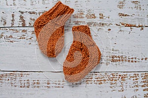 Soft and chunky, warm baby socks, hand-knitted, on white wooden background