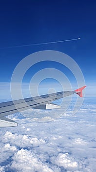 Soft clouds cover the sky during the flight. View of the wing of an airplane flying above the clouds at high altitude