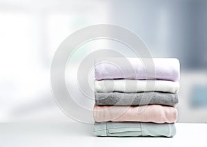 Soft colors stack of clothing,clothes folded on table empty copy space background.Garment stacked