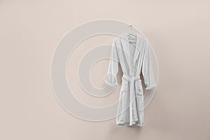 Soft comfortable bathrobe hanging on wall, space for text