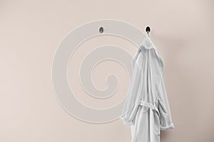 Soft comfortable bathrobe hanging on wall, space for text