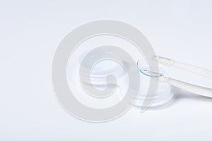 Soft contact lenses with solution, container and tweezers on white background with place for text. Macro photography