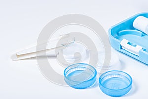 Soft contact lenses with solution, container and tweezers on white background with place for text. Macro photography