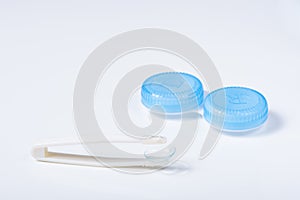 Soft contact lenses with solution, container and tweezers on white background with place for text. Macro photography