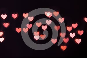 Soft defocused bokeh background with pink hearts, light from garland with open camera aperture, valentin`s day background