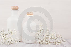 Soft elegant home decor with white bottles and small flowers on white wooden plank for advertising, designers, branding identity,