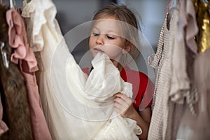 Soft Focus of a 5-6 Years Old Child Choosing her own Dresses from Kids Cloth Rack in Clothing Shop. Shopaholics Girl