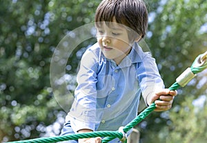 Soft focus of active kid climbing rope in the playground, High key light portrait Child enjoying activity in a climbing adventure