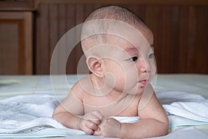 Soft Focus on Adorable curious infant  baby lay on stomach on the bed after taking a bath