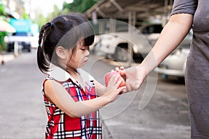 Soft Focus. Arm of mother is delivering red apple to daughter. Little girl used two hands to hold fruit.