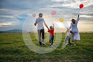 Soft focus of Asian family holding the balloon and walking on the Meadow at sunset with happy emotion. Family Holiday and Travel