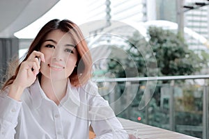 Soft focus of attractive young Asian business woman talking on phone in office with copy space background.