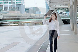 Soft focus of attractive young Asian business woman walking and looking far away at sidewalk of urban city background.