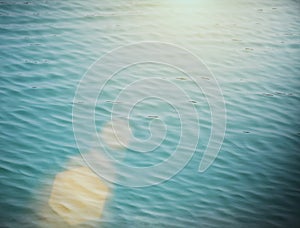Soft focus of blue water wave with flare. Vintage filtered nature background.