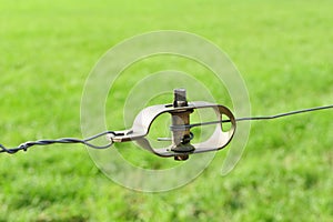 Soft focus of a fencing wire tensioner at a grassy field