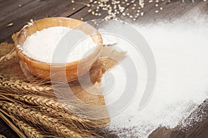 Soft focus, flour in a wooden bowl, ears of wheat, barley, cooking, bread, and cookies arranged on a wooden tabletop in a rustic