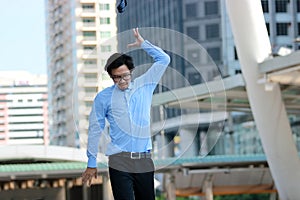 Soft focus of frustrated stressed young Asian businessman walking and throwing his necktie in urban building city background.