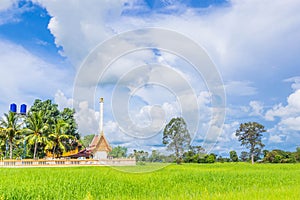 The soft focus of green paddy rice field with funeral pyre,crematorium, temple, beautiful sky and cloud in Thailand.