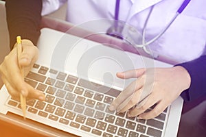 Soft focus of hand typing the keyboard of laptop and holding pencil, the doctor working at hospital office