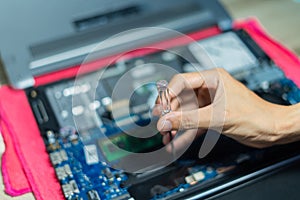 Soft focus, hand is using a screwdriver to tighten the nut. To change the battery of a notebook computer by yourself. Changing