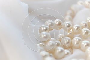 The soft focus on the pearls exudes a gentle, soothing aura on a pristine white fabric. It subtly champions the cause of