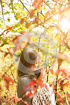 Soft focus photo. Beautiful girl drinking coffee in autumn wood. A cup with hot drink. Cosy mood. Red and yellow leaves. Beautiful