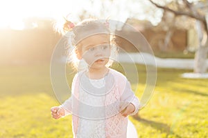 Soft focus photo of little curly girl with two tails walking in the backyard on the green grass