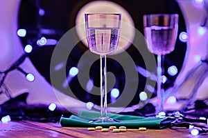 Soft focus photo of two glasses of champagne and pills on the background of a vinyl record, surrounded by bright club illumination