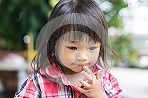 Soft focus. Portrait image of baby 1-2 years old. Asian child girl put her hands and in her mouth and biting her fingers at the