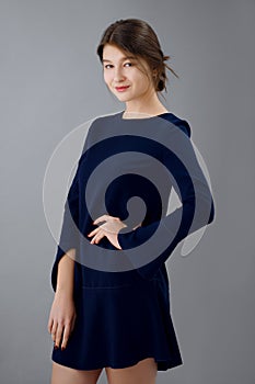 Soft focus portrait of pretty girl in short blue dress posing on gray background