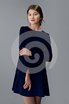 Soft focus portrait of pretty girl in short blue dress posing on gray background