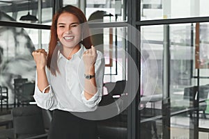 Soft focus of smiling young Asian businesswoman raising hands in office. Successful business woman concept.