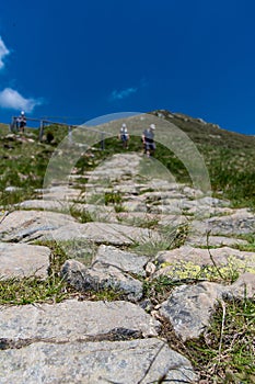 Soft focus of a stone path on a mountain with a group of hikers in the background