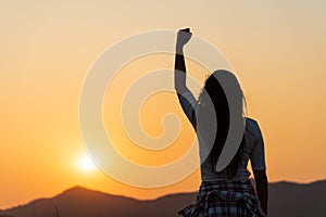 Soft focus of woman with fist in the air during sunset sunrise mountain in background. Stand strong. Feeling motivated, freedom,