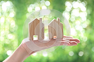 Soft focus of Woman hand holding model house on natural green background, Business investment and real estate concept