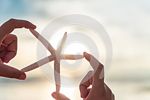 Soft focus on woman hand holding starfish over sea and Sandy