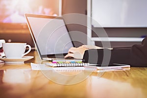 Soft focus of woman hand working laptop on wooden desk in office in morning light.