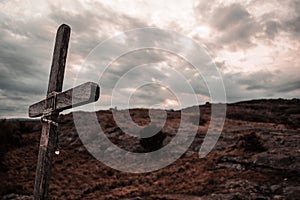 Soft focus of a wooden cross on a rocky field under a cloudy sky in the mountains of Mallin