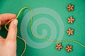 Soft focus on wooden snowflakes with christmas golden beads in blurry hand. Holiday background. Christmas and New Year