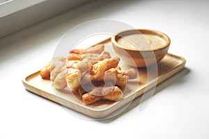 Soft focus of Youtiao or Cakwe with milktea custard on brown wooden background. Thailand street food  is call `Patongo`.