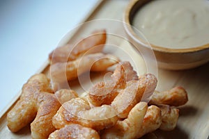 Soft focus of Youtiao or Cakwe with milktea custard on brown wooden background. Thailand street food  is call `Patongo`.