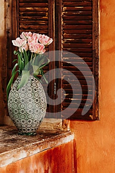 A soft focused bouquet of flowers in an old vase on a window sill