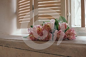 A soft focused bouquet of flowers on a window sill, dull light