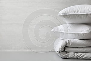 Soft folded blanket and pillows on light grey table, closeup. Space for text