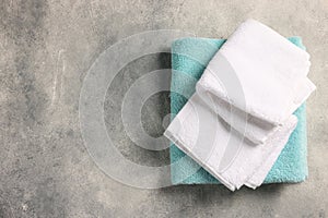 Soft folded terry towels on light gray textured background, top view. Space for text