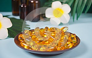 Soft gelatin capsules. Natural vitamins supplement. Vitamin A, E, fish oil, primrose oil. Tropical background