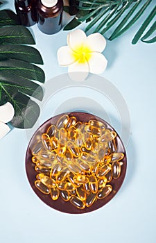 Soft gelatin capsules. Natural vitamins supplement. Vitamin A, E, fish oil, primrose oil. Tropical background