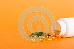 Soft gels pills with Omega-3 oil spilling out of pill bottle close-up. Gel capsules bottle white surface. Omega 3