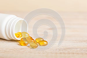 Soft gels pills with Omega-3 oil spilling out of pill bottle close-up. Gel capsules bottle white surface. Omega 3