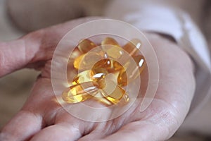 Soft gels pills with Omega-3 oil spilling out of pill bottle close-up iin open hand